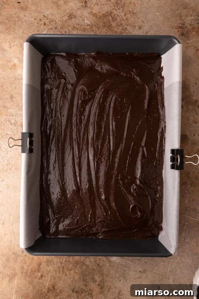 Brownie batter spread evenly in a baking pan