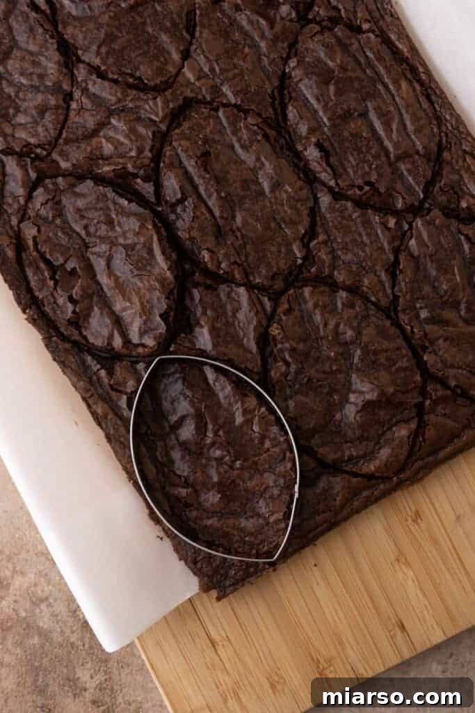 A football cookie cutter pressing into a baked brownie