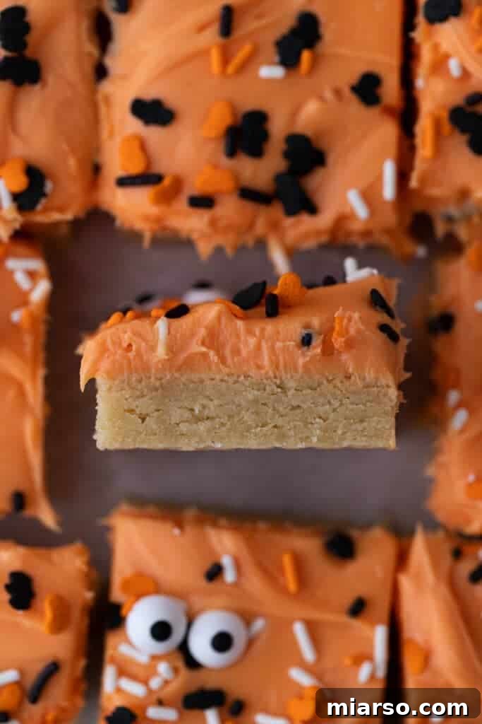 Spooktacularly Simple Halloween Sugar Cookie Bars 10 A plate of Halloween sugar cookie bars with orange frosting and sprinkles