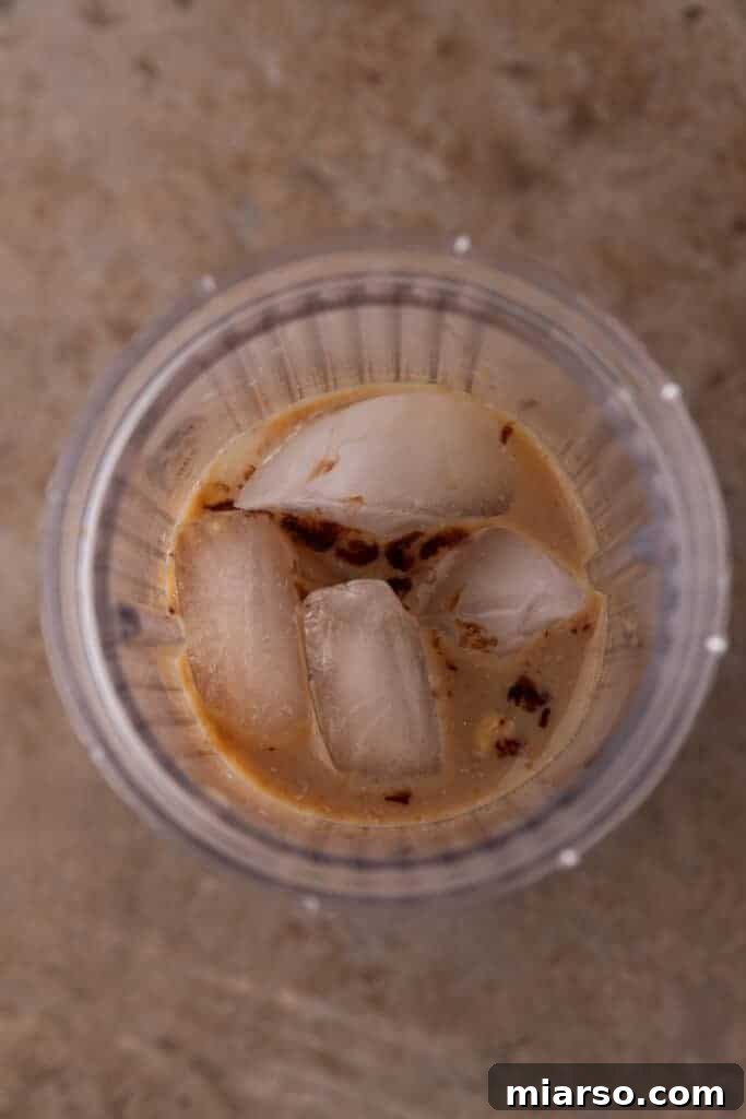 All liquid ingredients and ice being added to a blender for the Frappuccino.