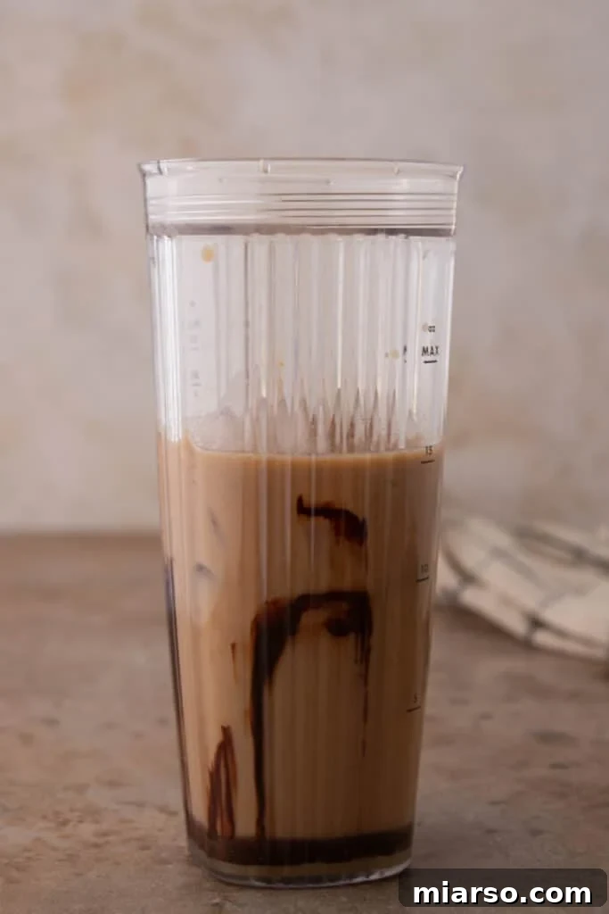 Close-up view of liquid ingredients and ice ready for blending in a blender.