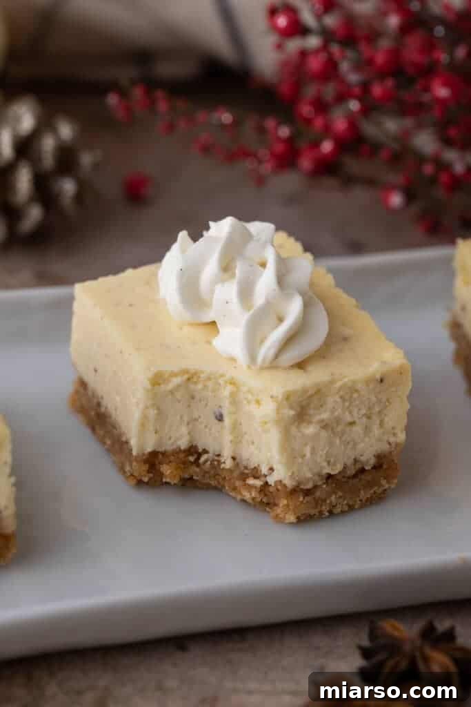 A single eggnog cheesecake bar with a bite taken out, showcasing its creamy interior and crust