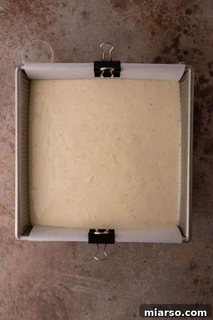Smooth cheesecake batter poured into a baking pan with a graham cracker crust