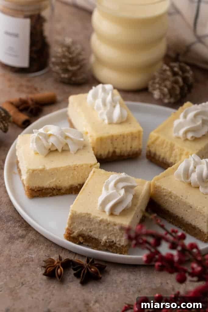 Multiple creamy eggnog cheesecake bars lined up in a circle, showcasing their golden crust and smooth topping