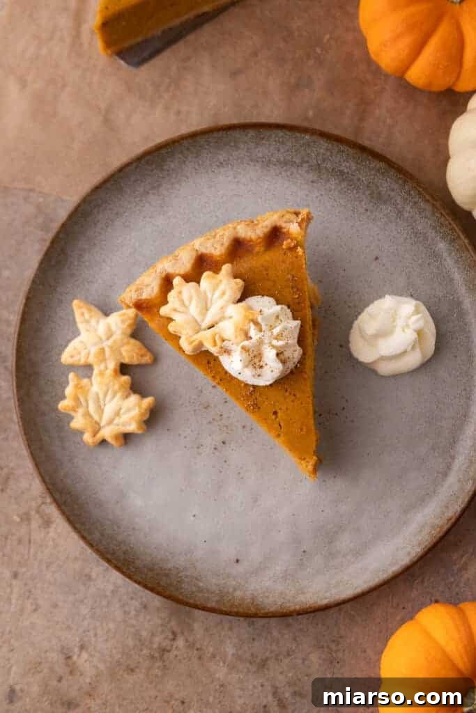 Double the Delight: The Ultimate 9-Inch Pumpkin Pie Recipe 14 A delightful slice of pumpkin pie on a plate, elegantly served with a dollop of whipped cream on the side.