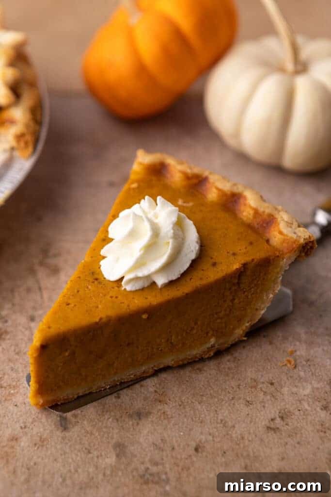 Double the Delight: The Ultimate 9-Inch Pumpkin Pie Recipe 15 A beautiful slice of baked pumpkin pie, resting on a spatula above a rustic wooden table.