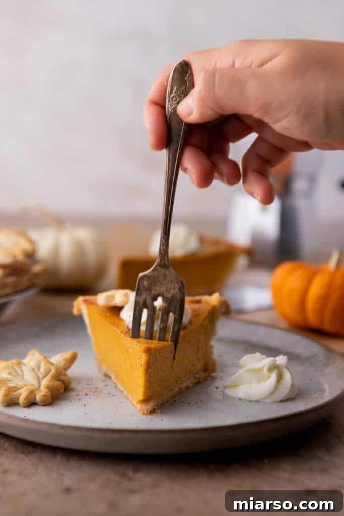 Double the Delight: The Ultimate 9-Inch Pumpkin Pie Recipe 5 A fork piercing into a delicious slice of pumpkin pie, revealing its creamy texture and flaky crust.