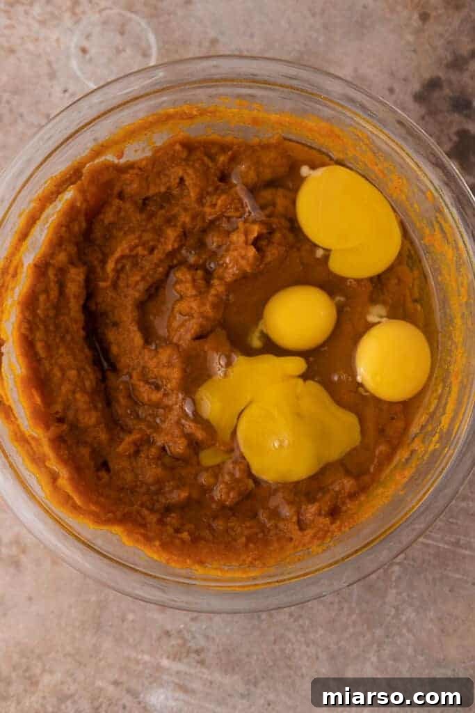 Double the Delight: The Ultimate 9-Inch Pumpkin Pie Recipe 7 A mixing bowl containing pumpkin puree and whisked eggs, captured mid-preparation for the pumpkin pie filling.