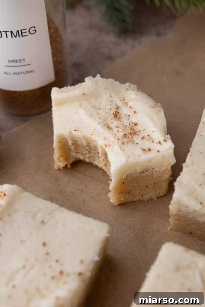An eggnog cookie bar with a bite taken out, showcasing the soft texture and frosting