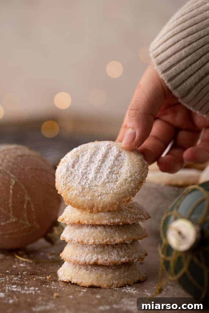 multiple melting moments cookies stacked on top of each other with the top one being held up by a hand