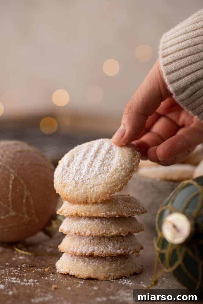 a stack of melting moments cookies with the top one being lifted up by a hand