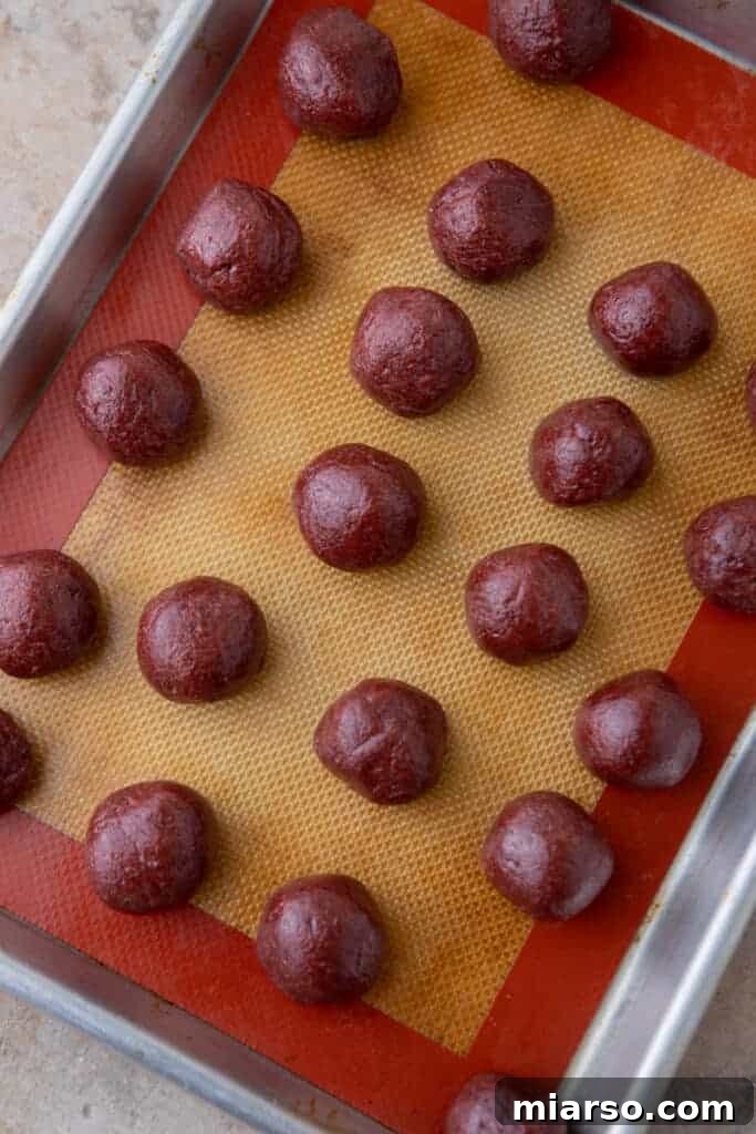 a bunch of rolled out uncoated grinch oreo truffles laid out on a baking sheet
