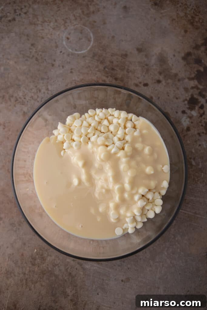 White chocolate chips melting in a bowl with sweetened condensed milk.