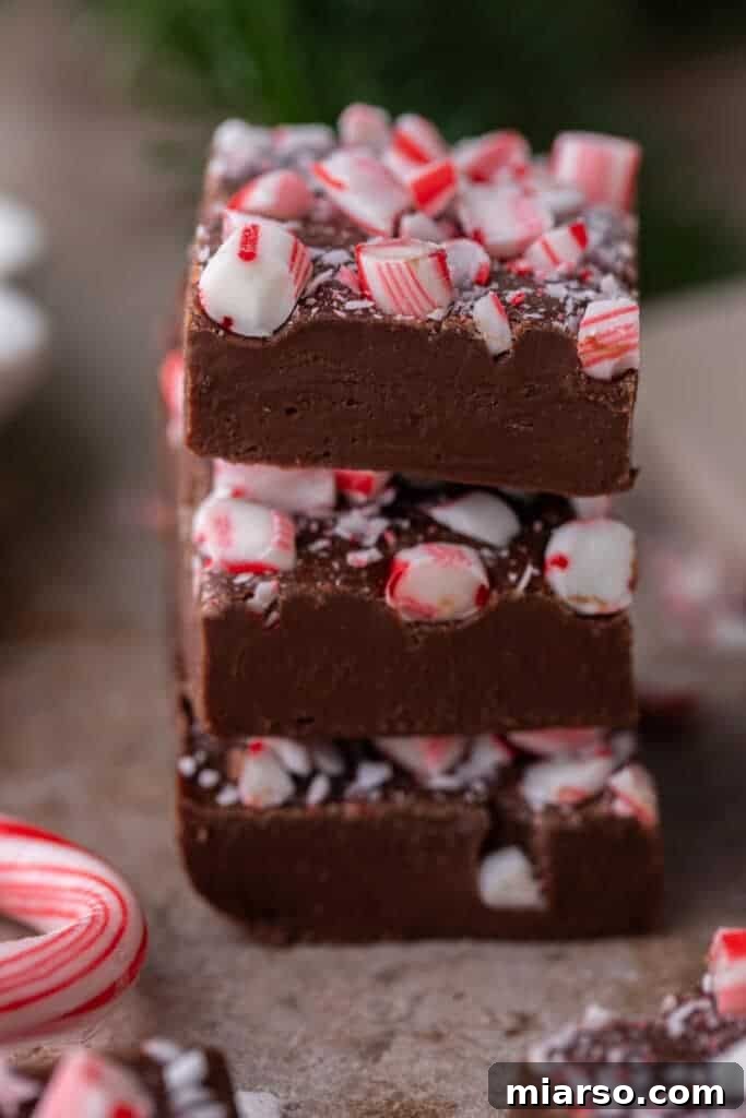 A stack of three decadent chocolate peppermint fudge squares, showcasing their rich texture.