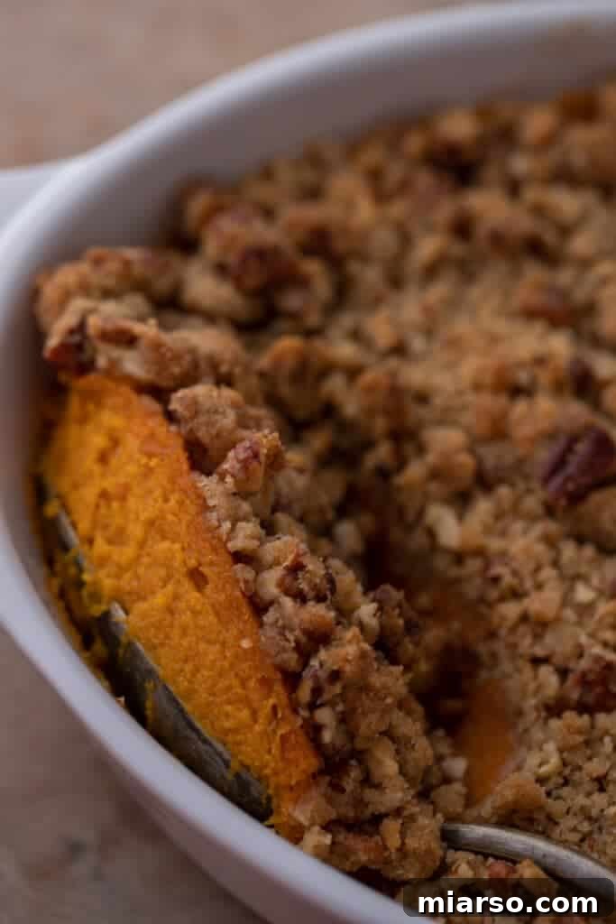 Pecan-Topped Sweet Potato Perfection 2 a spoon digging into a sweet potato casserole with pecans