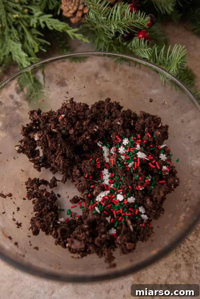 Crumbled chocolate Christmas tree cakes in a bowl with red, green, and white sprinkles mixed in.