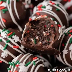 Close-up of a chocolate Christmas tree cake truffle with a fudgy center, white drizzle, and festive holiday sprinkles.