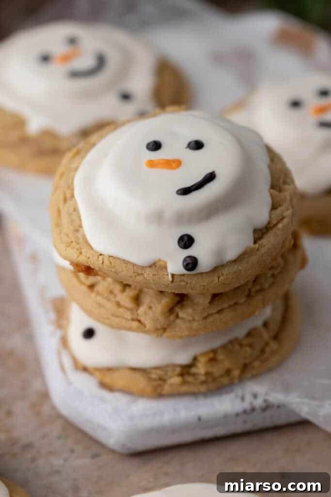 Angled overhead shot of three adorable melted snowman peanut butter cookies, perfect for holiday gatherings.