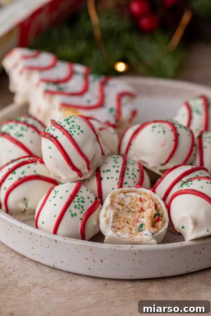 Easy No-Bake Little Debbie Christmas Tree Truffles 2 A bowl filled with multiple Little Debbie Christmas Tree Cake Truffles, one with a bite taken out, showcasing the soft vanilla cake interior.