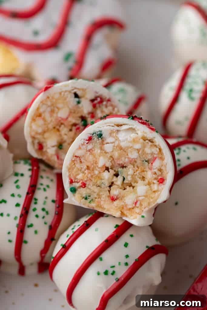 Easy No-Bake Little Debbie Christmas Tree Truffles 13 A close-up view of a Little Debbie Christmas Tree Cake Truffle cut in half, revealing the vibrant, sprinkle-filled vanilla cake interior.