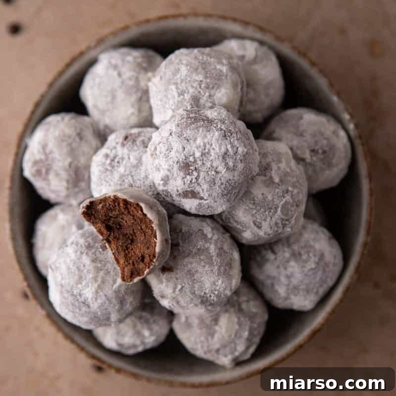 Bowl of powdered sugar–coated chocolate cookies with one cookie broken open.
