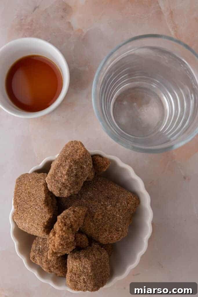 Fresh ingredients laid out for making homemade Starbucks brown sugar syrup: brown sugar, cinnamon stick, vanilla extract, and water.
