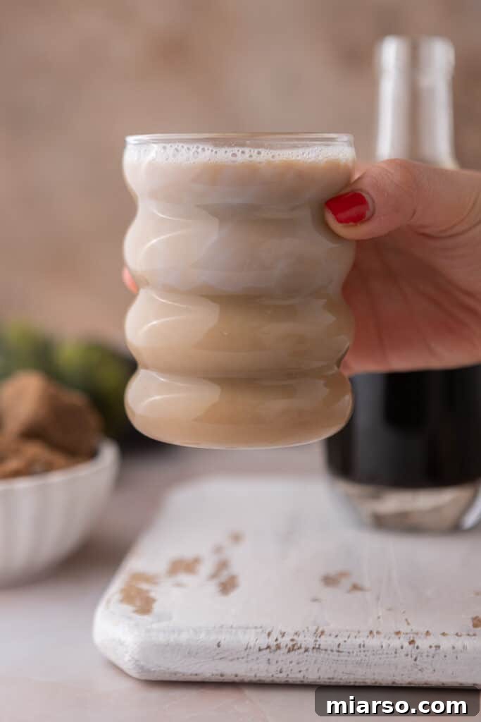 A hand holding a mug of coffee with homemade brown sugar syrup, ready to be enjoyed.