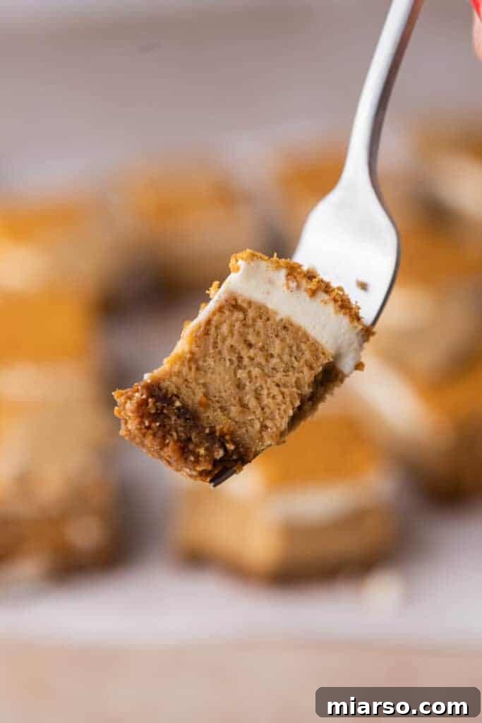 A single gingerbread cheesecake bar on a fork, showing its creamy texture and crumbly crust.
