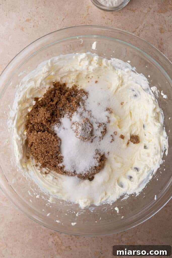 Unmixed ingredients for the cheesecake batter, including softened cream cheese and sour cream in a bowl.