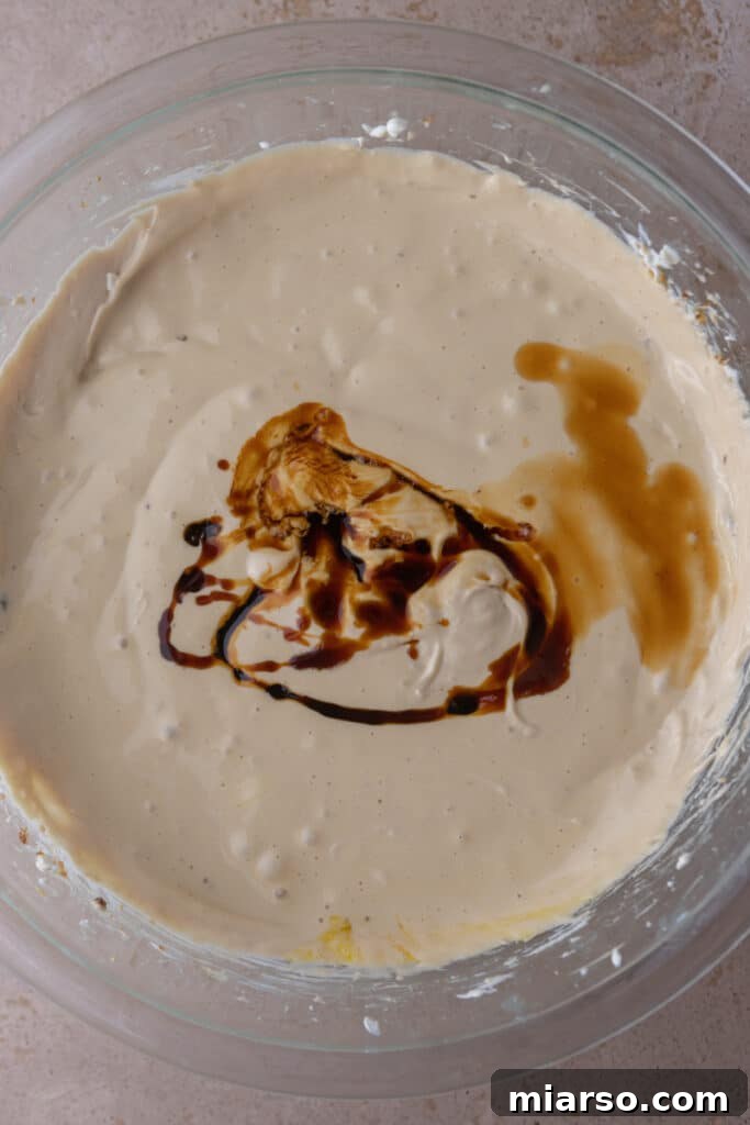 Vanilla extract and rich molasses being added to the cheesecake batter for depth of flavor.