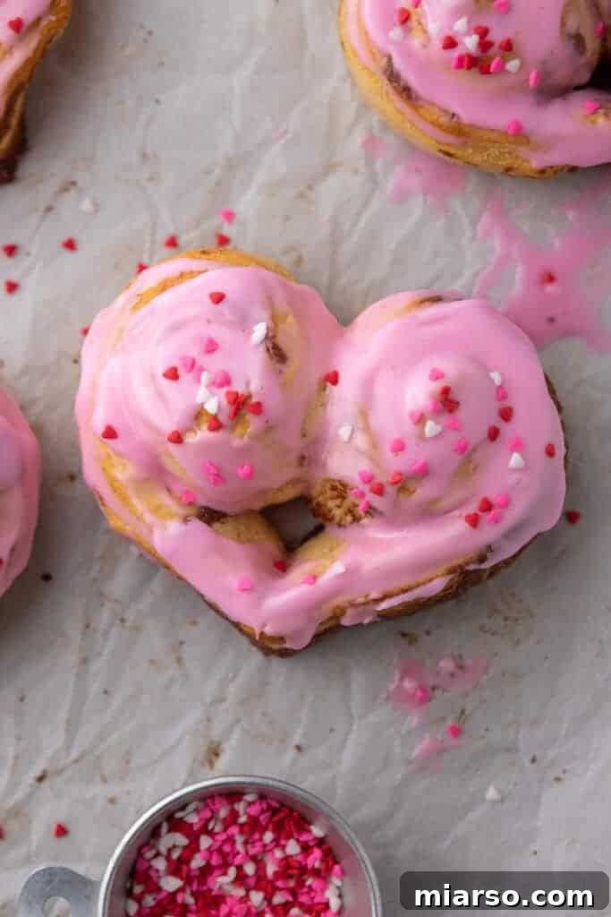 Heart-shaped cinnamon rolls with pink icing and sprinkles