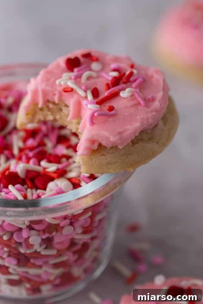 Ultimate Valentine Frosted Sugar Cookies 12 A close-up of a Valentine's Day frosted sugar cookie with a bite taken out, showing the soft interior