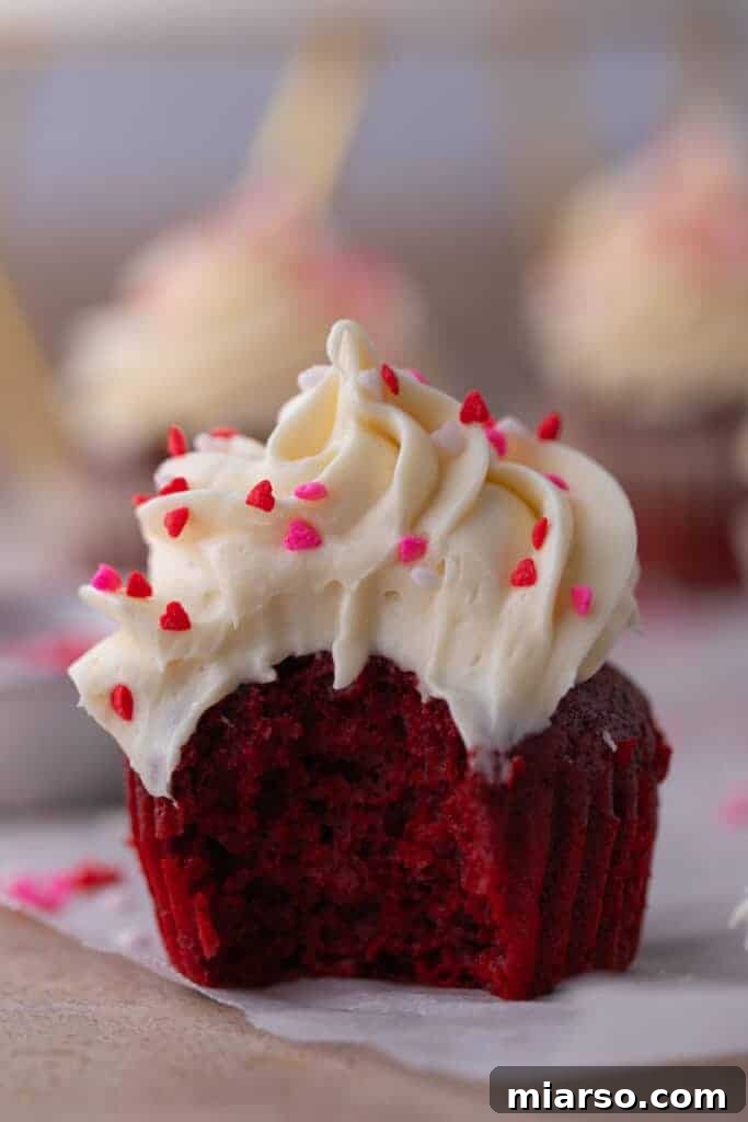 A close-up of the small batch red velvet cupcake with a bite taken out, highlighting the velvety texture and creamy frosting.