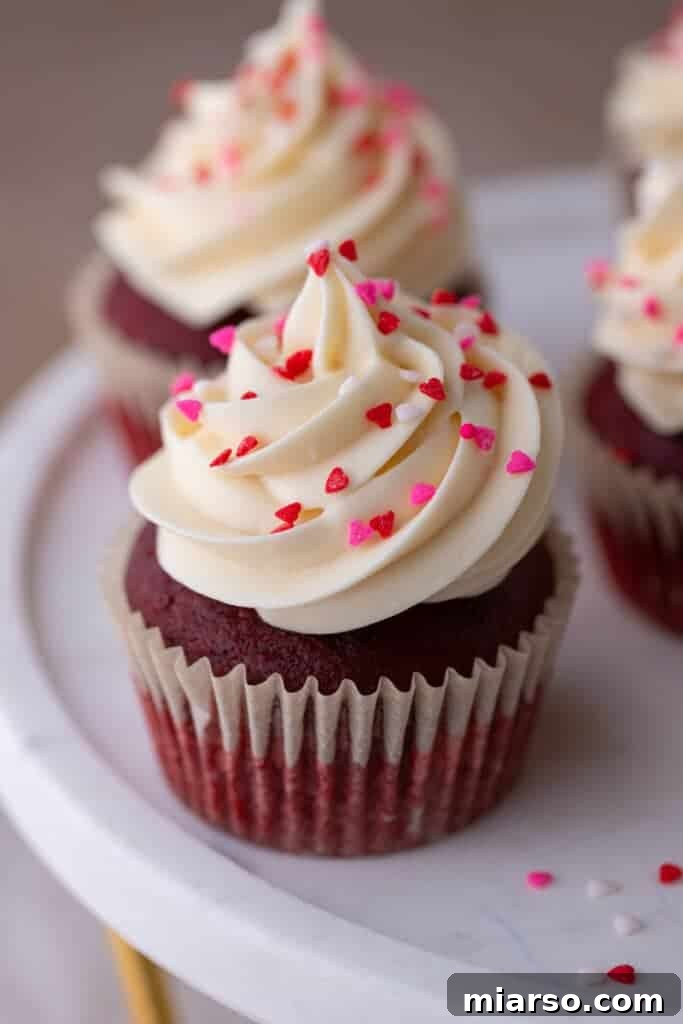 A beautifully decorated small batch Red Velvet cupcake, showing the swirl of cream cheese frosting.
