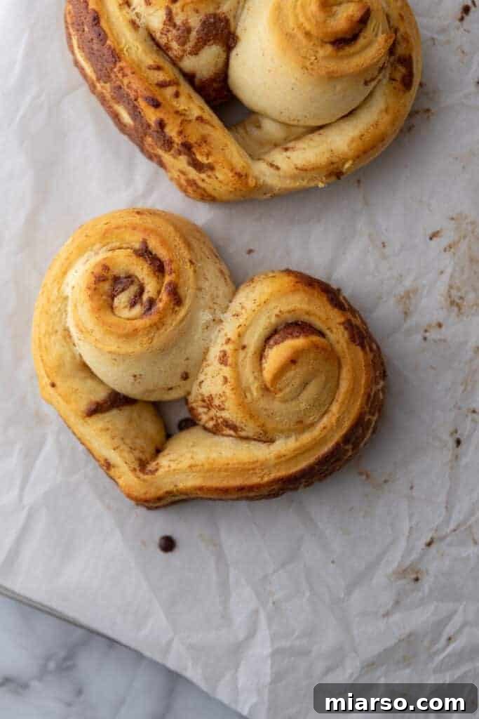 Valentines Sweetheart Cinnamon Buns Made Easy 12 An un-iced Valentine's Day heart-shaped cinnamon roll, freshly baked and golden brown, showcasing its perfect shape before frosting.