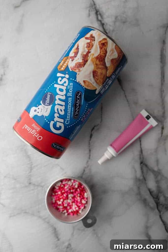 Valentines Sweetheart Cinnamon Buns Made Easy 3 Essential ingredients for making Valentine's Day heart-shaped cinnamon rolls, neatly laid out on a clean surface, including canned dough, sprinkles, and food coloring.
