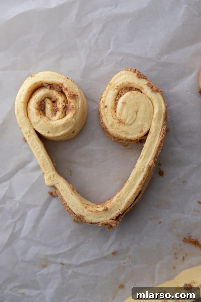 Valentines Sweetheart Cinnamon Buns Made Easy 6 A strip of cinnamon roll dough partially rolled from each side, demonstrating the beginning of the heart-shaping process.