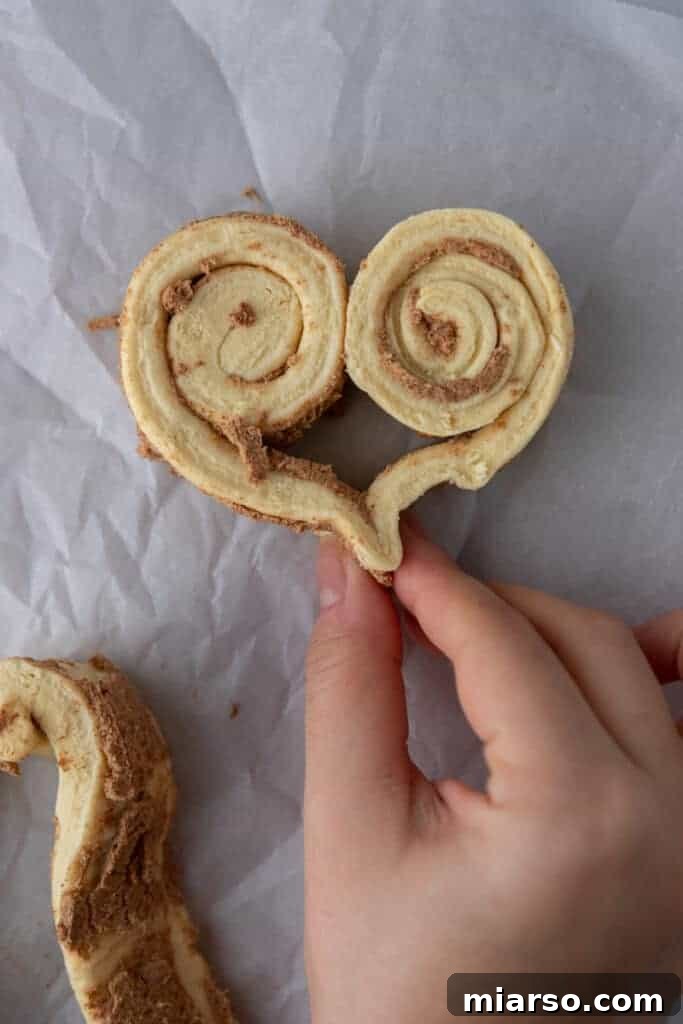 Valentines Sweetheart Cinnamon Buns Made Easy 7 A cinnamon roll dough fully rolled and pinched into a perfect heart shape, ready for baking.
