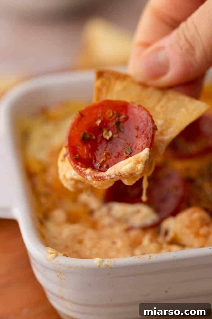 A delectable scoop of high-protein cottage cheese pizza bowl dip on a crispy chip, ready to be enjoyed.