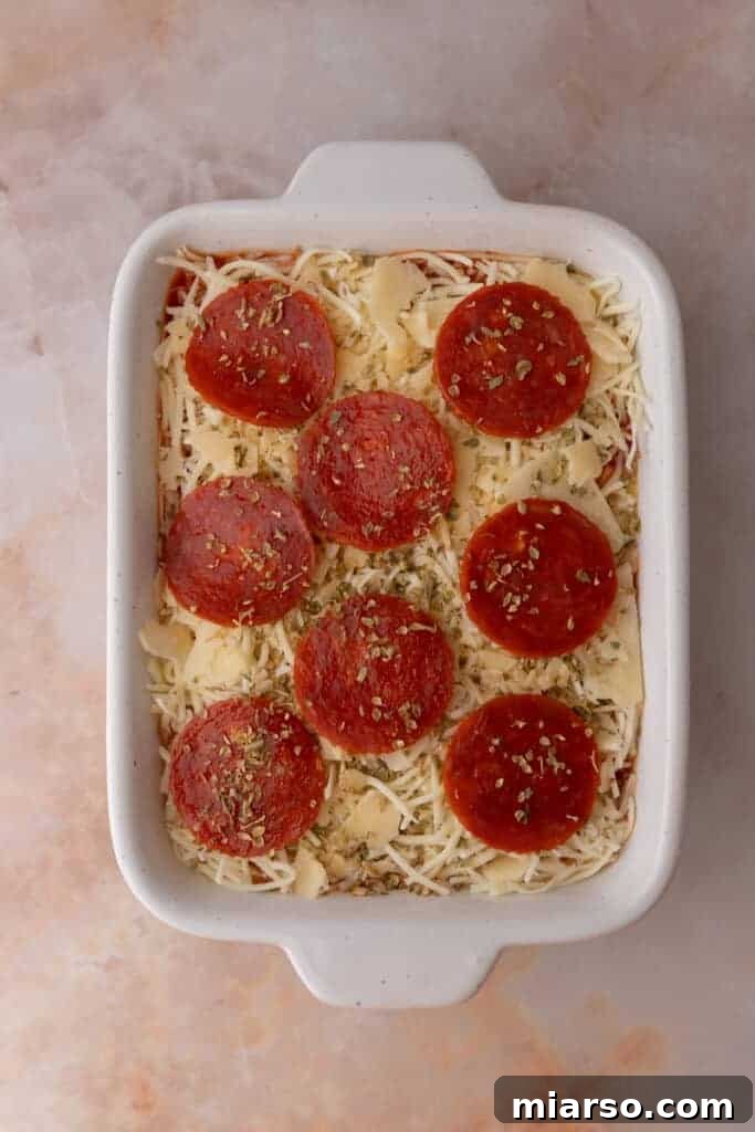 Savory turkey pepperoni slices artfully arranged over the cheese layer, awaiting baking.