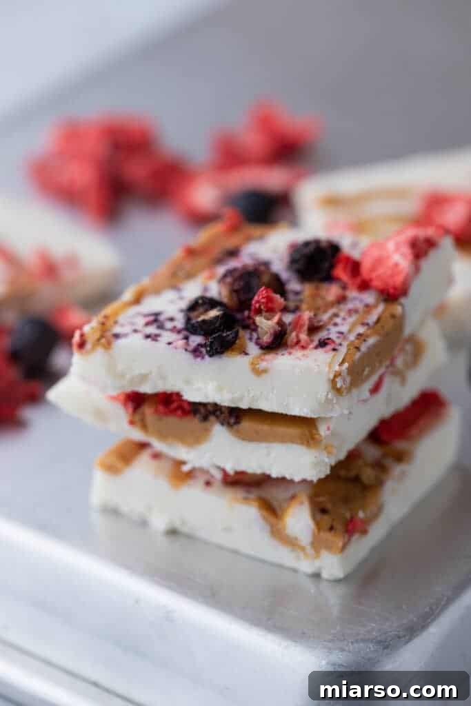 Protein Packed Cottage Cheese Freezer Bark 4 Several neatly stacked squares of frozen cottage cheese bark, showcasing the creamy texture and berry toppings.
