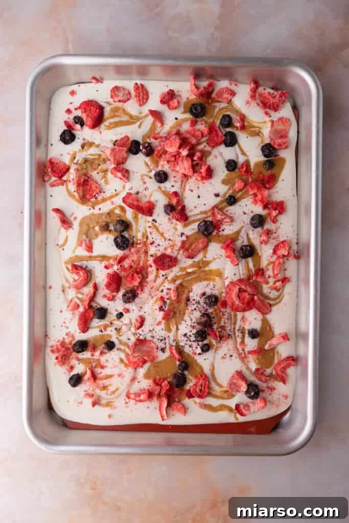 Protein Packed Cottage Cheese Freezer Bark 8 A finished sheet of frozen cottage cheese bark, with peanut butter swirls and berry toppings, chilling on a baking pan.