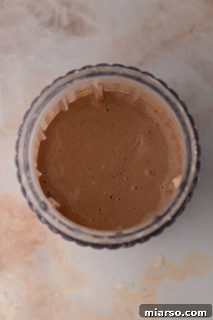 Fully mixed chocolate milkshake ingredients, now a smooth liquid, inside a blender cup.