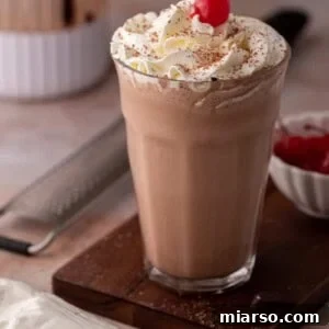 side view of the chocolate milkshake recipe with a blender behind it