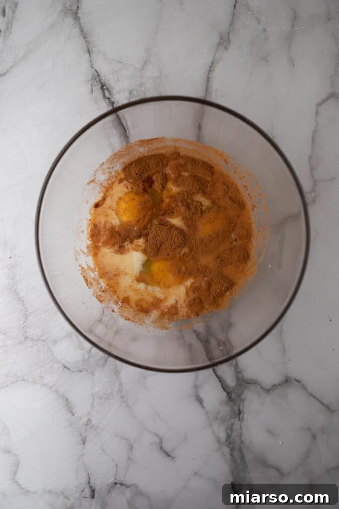Close-up of the French toast batter ingredients being whisked together in a bowl, creating a smooth, creamy mixture.