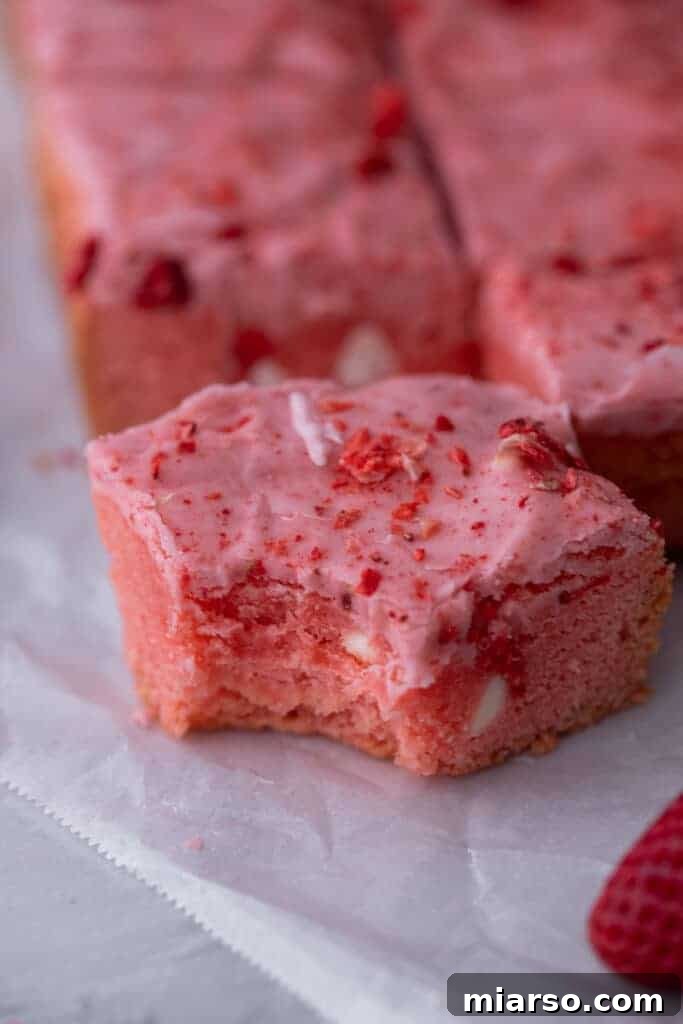 Irresistibly Easy Strawberry Brownies from a Cake Mix 4 Close-up view of a single strawberry brownie with a bite taken out, revealing its dense, fudgy interior and pink hue.
