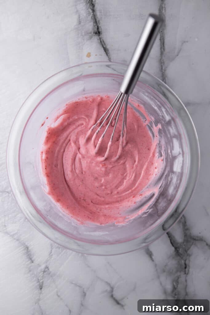 Irresistibly Easy Strawberry Brownies from a Cake Mix 9 Pink strawberry glaze being whisked in a bowl.