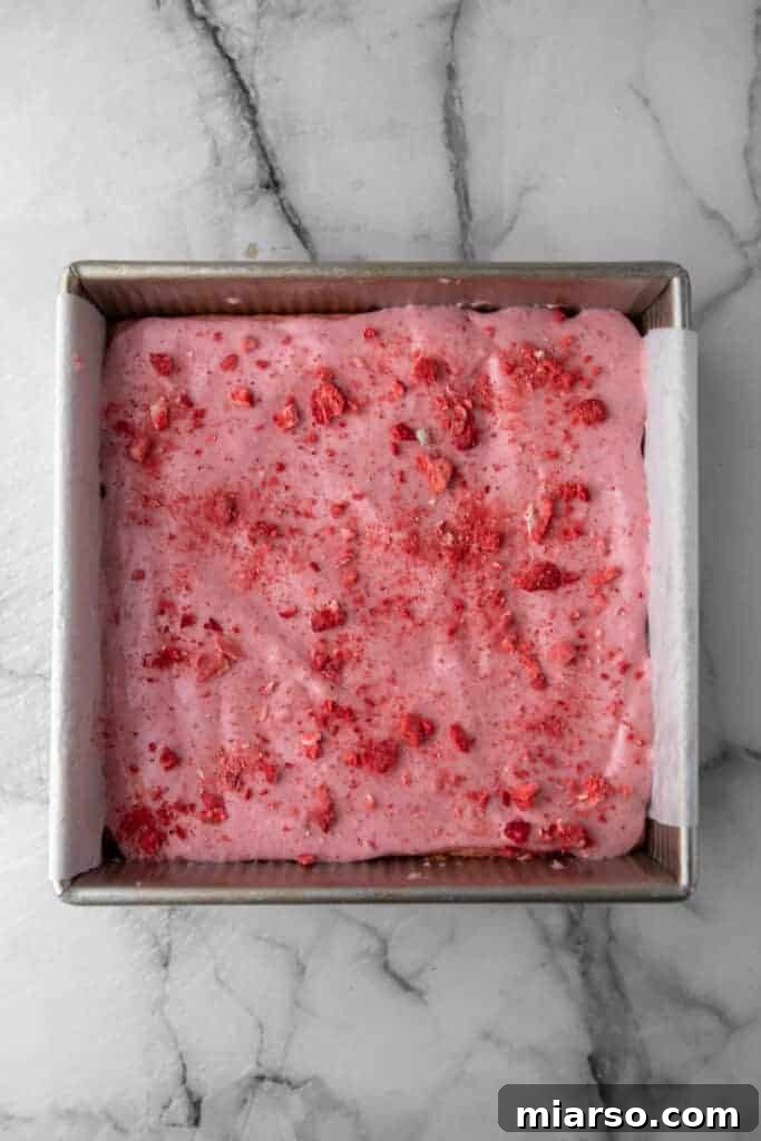 Irresistibly Easy Strawberry Brownies from a Cake Mix 10 Fully glazed strawberry brownies in the baking pan, ready to be sliced.
