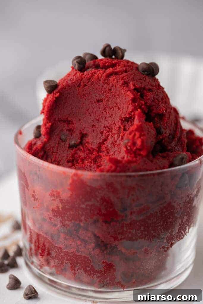 Close up of red velvet cookie dough, showing its vibrant red color and chocolate chips.