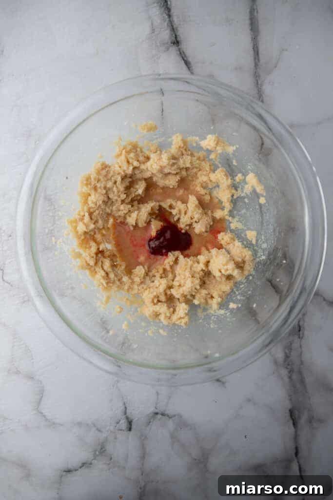 Close-up of softened butter and sugars being creamed together in a mixing bowl.